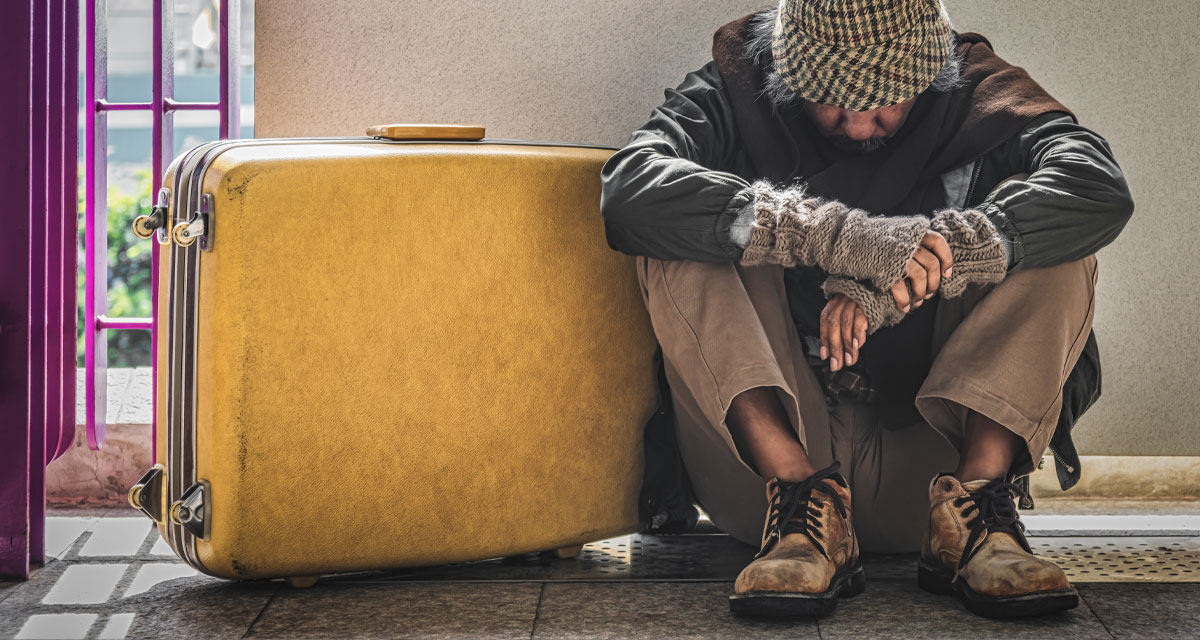 man sitting on group with yellow suitcase