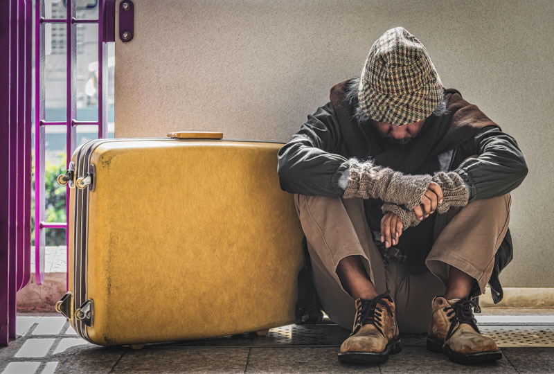 man sitting on group with yellow suitcase