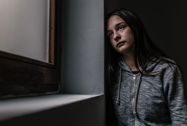 young girl leaning against wall